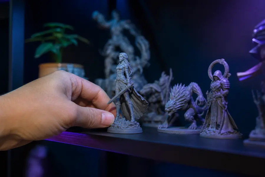Main posant une figurine imprimée en 3D sur une étagère